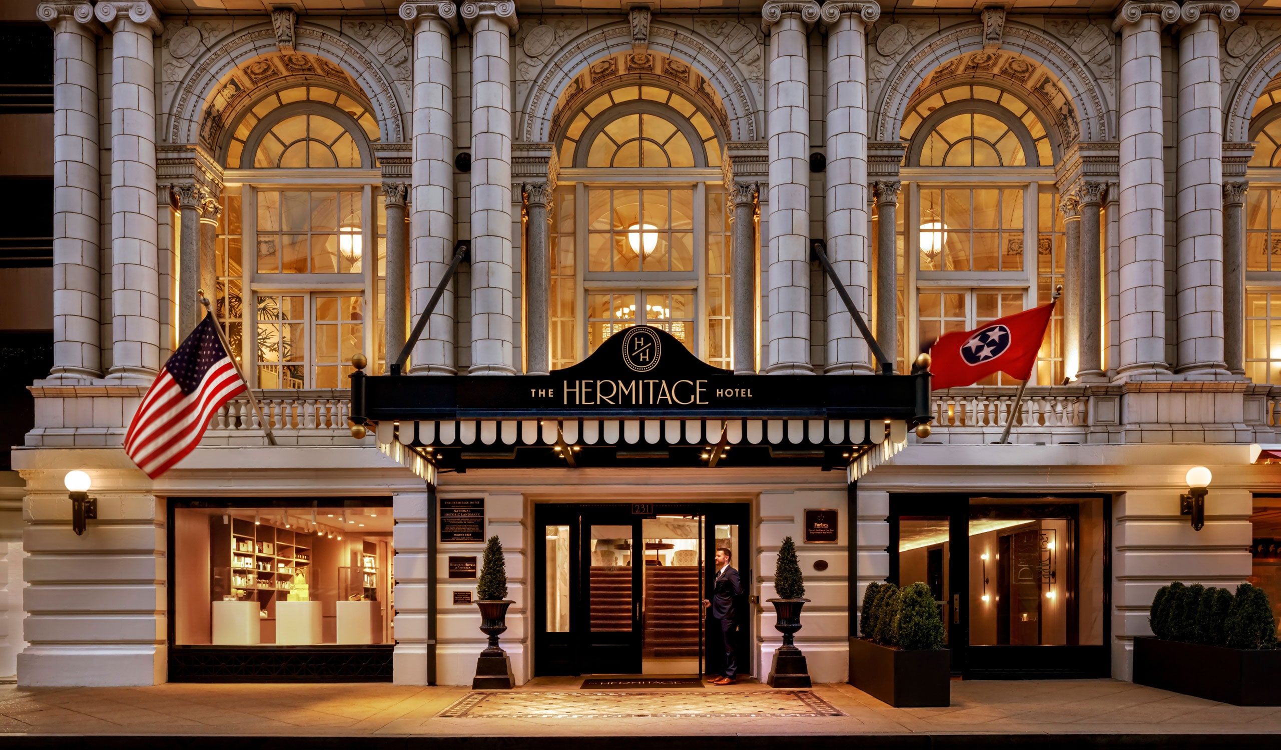 The Hermitage Hotel exterior at dusk, with US and Tennessee flags flanking the entrance